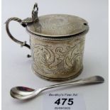 A silver drum shaped mustard pot with engraved foliate and scroll design and double scroll acanthus