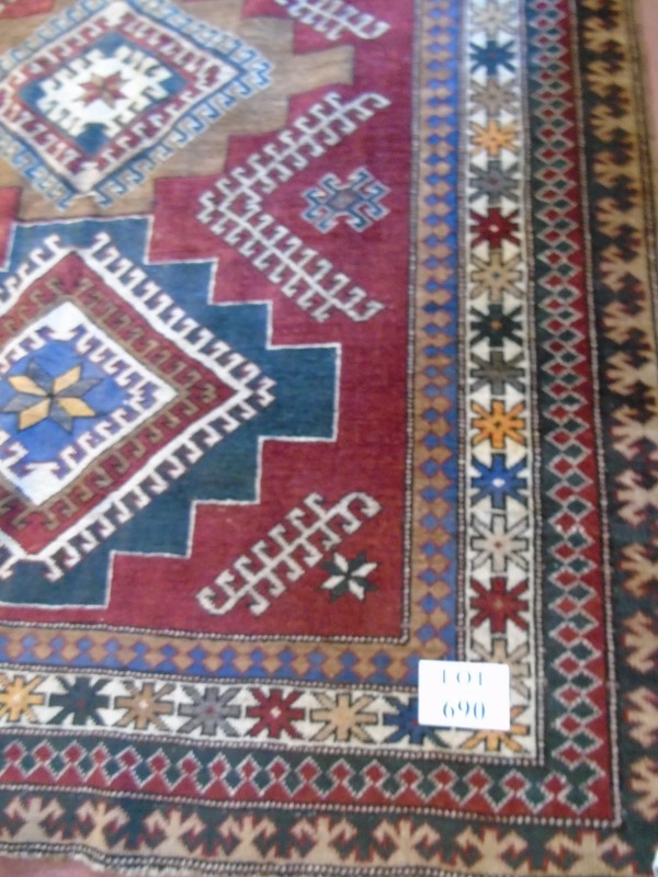 A Caucasion rug with three diamond motifs to center surrounded by a four layer border.