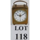 A small brass cased antique alarm clock with enamelled dial and Arabic numerals.