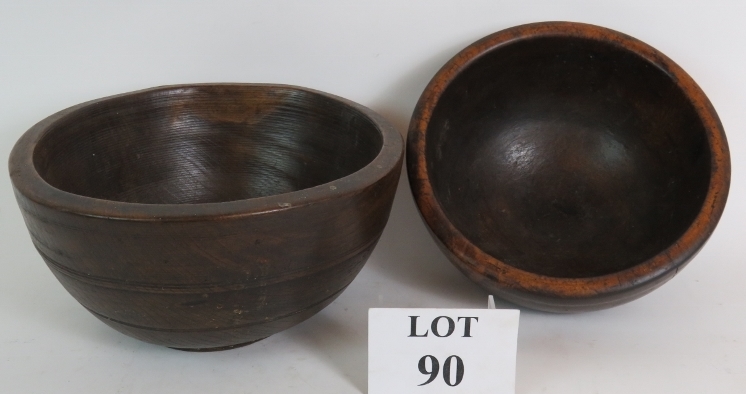 Two antique turned oak or elm dairy bowls, the larger being 29cm in diameter,