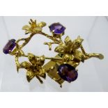 A 9ct gold lily design open work brooch, set with three oval amethysts,