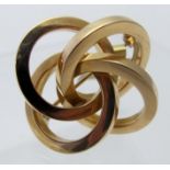 A stylish contemporary yellow metal brooch in the form of an eternal knot,