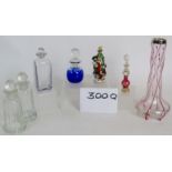 A porcelain scent bottle of 3 children decorating a tree, two coloured glass scent bottles,