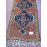 An early-mid 20's Turkish runner with repeated central motif on a red ground and tan border.