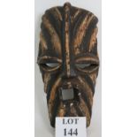 A decorative ethnic African tribal mask with striped decoration. Carved from one piece of wood.