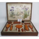 An oak boxed silk lined vanity set with Amber Celluloid accessories, some missing.