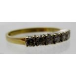 An 18ct gold ring set with a band of seven diamonds, size O, boxed.