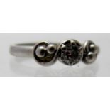 A diamond solitaire ring set in silver, with scroll and ball decoration, size M.