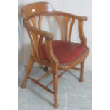 An early 20th Century light oak framed captain's desk chair with a burgundy leather seat and