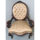 A Victorian decoratively carved mahogany spoon back nursing chair upholstered in a cream and gold