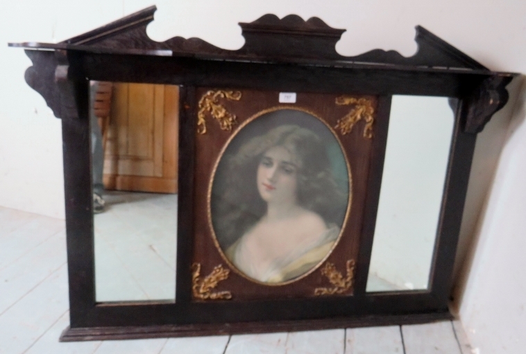 A decorative oak framed over mantle mirror with a central inset oval print depicting a portrait