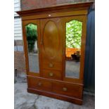 An Edwardian inlaid mahogany wardrobe with a central oval panelled cupboard door over two small