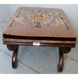A small 19th Century mahogany framed stool with a floral tapesty top and having decorative brass