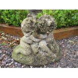 A small garden reconstituted stone statue modelled as two cradling cherubs, nicely weathered.