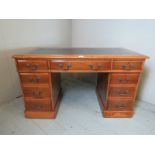 An Edwardian mahogany and oak pedestal desk with an inset tooled blue / black leather top over an