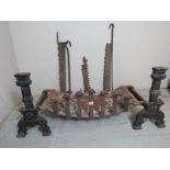 A cast iron fire basket raised on a pair of fire dogs together with three iron pot hooks / fire