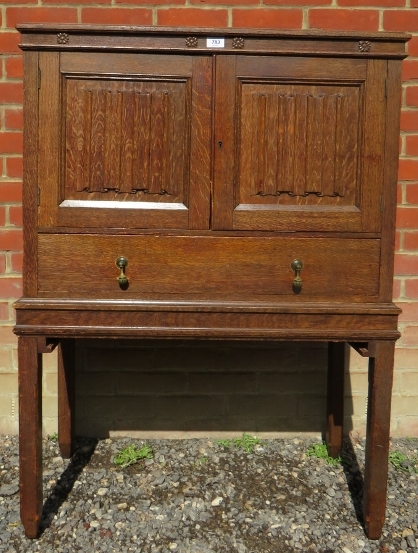 A period-style oak collectors cabinet with linen fold panelled doors opening to reveal an