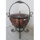A decorative vintage copper coal bucket or jardiniere with an ironwork basket frame with rope twist