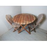 A teak folding circular garden table complete with four matched folding garden chairs.