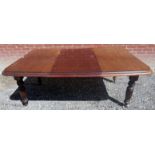 A mahogany extending wind out dining table with an Edwardian base having fluted legs beneath a