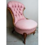 A Victorian walnut framed nursing chair upholstered in a pink button back material and terminating