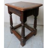 A 17th Century and later country oak joint stool with a carved linen fold frieze over turned