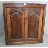 A rustic 18th Century country oak cupboard with two doors having arched panels opening to reveal a