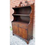 A 20th Century mahogany waterfall bookcase with two small drawers over cupboard doors to base.