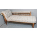 A 19th century show wood chaise lounge upholstered in a pale cream and blue fabric.