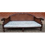 A large 19th Century carved oak framed bergere settee with decorative scroll arms over a floral