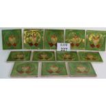 A set of 12 Art Nouveau style fireplace tiles with central lily motif on a green background.