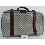 a vintage Gucci suitcase with navy and grey lattice logo design. Size: 67cm x 39cm x 20cm.