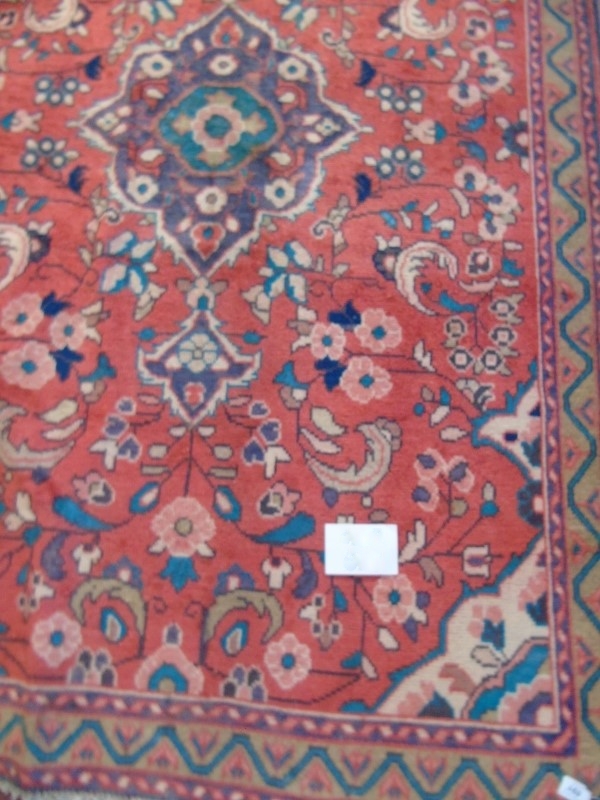 A Hamadan rug on red ground with central motif surrounded by flowers.