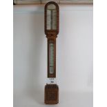 A large carved oak Victorian stick barometer enamelled panels and adjustable pressure bars.