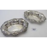 A pair of silver bon bon dishes with pierced decoration and embossed with flowers and scrolls,