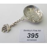 A white metal Dutch caddy spoon. The bowl embossed with windmill and house and a ship finial.