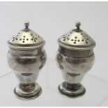 A pair of small Victorian silver vase shaped peppers, Sheffield 1887. Small dents.