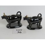 A pair of antique black glazed cow creamers with gilt decoration, probably Staffordshire.
