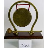 A vintage brass dinner gong on oak stand by 'Nestor' of England. Height: 30cm.