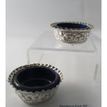 A pair of Victorian silver salts, embossed with foliate design, gilt interiors and blue liners,