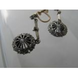 A pair of white metal drop earrings, terminating in a web design,