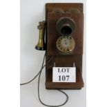 A vintage wall mounted telephone with brass earpiece, two integral bells and shelf for message pad.