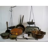 A large selection of mainly antique copper pans, iron ware, and two pairs of hanging balance scales.