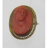 A 19th century yellow metal oval brooch with carved coral figure, possibly Apollo.