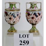 A highly decorative pair of antique Continental porcelain urns with relief moulded bodies depicting