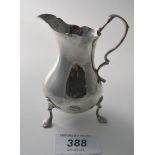 A Georgian silver baluster cream jug with double scroll handle and sitting on three cast trefoil