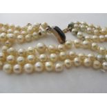A three strand vintage pearl necklace with probably a gold and garnet clasp and fine safety chain.
