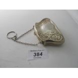A silver embossed purse on a chain, decorated with scrolls and flowers, inside replacement,