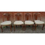 Set of four carved oak framed dining chairs upholstered in a cream material.