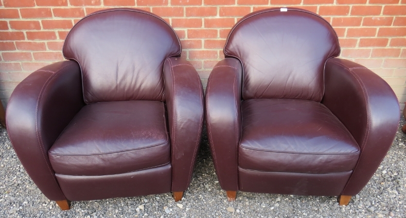 A pair of contemporary tub chairs upholstered in a deep brown / aubergine leather.